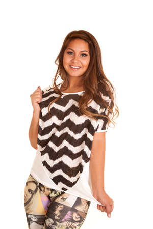 A woman playing with her shirt with a smile on her face.の写真素材