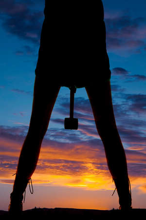 a silhouette of a woman holding onto a hammer.の写真素材