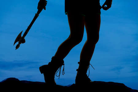 A silhouette of a woman's legs holding on to a hatchet.の写真素材