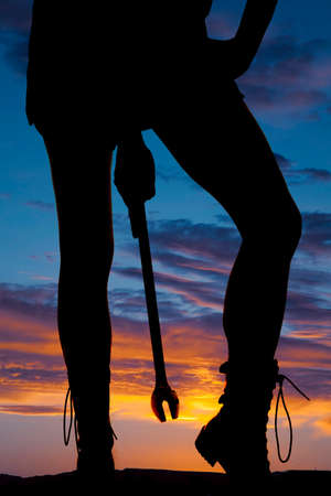 a silhouette of a woman holding on to a wrench between her legs.の写真素材