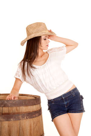 A cowgirl looking to the side leaning on her arm on a barrel.の写真素材