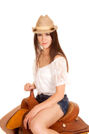 A woman in her hat sitting on a lether saddle.の写真素材