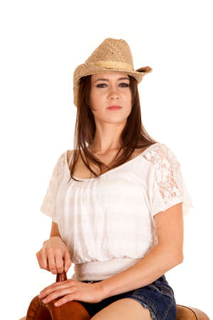 A brunette sitting on a saddle wearing her cowgirl hat.の写真素材