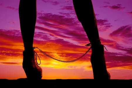 a silhouette of a woman legs with handcuffs on her ankles.の写真素材