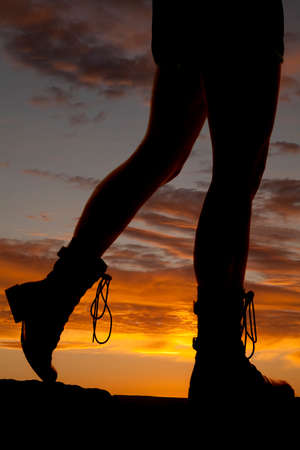 A silhouette of a woman with her legs showing, wearing her hiking boots.の写真素材