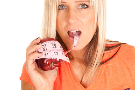 A woman holding on to an apple, with a measuring tape wrapped around it.の写真素材