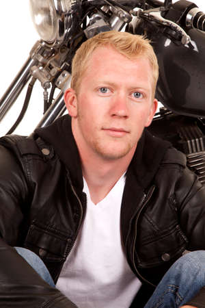 A man sitting in front of his motorcycle with a serious expression on his face.の写真素材