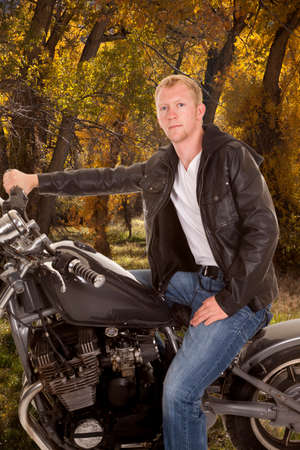 A man sitting on his motorcycle looking in the outdoors.の写真素材