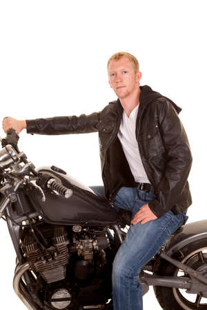A man sitting on his motorcycle in his leather jacket looking.の写真素材