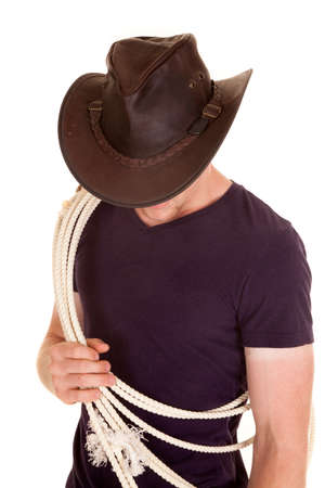 A cowboy with a rope over his shoulder, looking down and a hat on his head.の写真素材