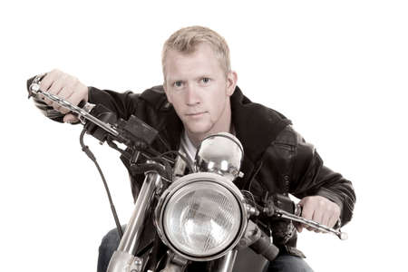 A black and white photo of a  man in his black leather jacket leaning over his handle bars.の写真素材