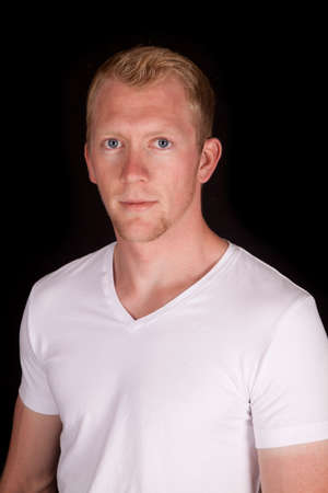 A man in his white t-shirt on a black background with a serious expression.の写真素材