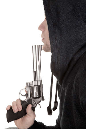 A profile of a man with a gun up to his mouth blowing on the barrel.の写真素材