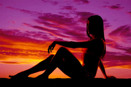 A woman sitting on the ground in her bikini relaxing.の写真素材