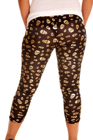 A woman with her back to the camera wearing black with gold skulls leggings.の写真素材
