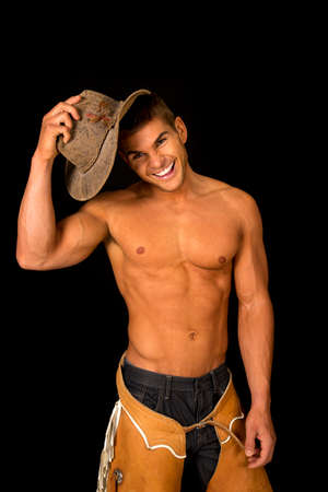 A cowboy with a smile putting his hat on his head on a black background.の写真素材