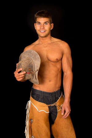 A cowboy with his hat by his bare chest smiling.の写真素材