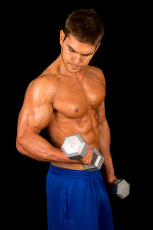 A man on a black background, with no shirt working out with weights.の写真素材