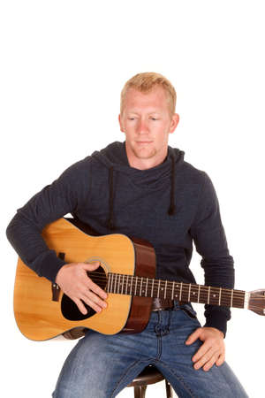 A man holding on to his guitar looking down.の写真素材