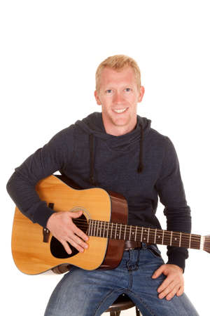A man with a smile on his face holding on to his guitar.の写真素材