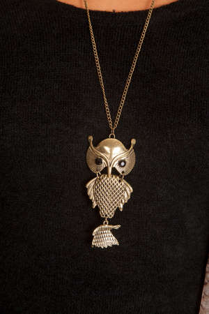 a close up of a woman wearing a owl pendant on her necklace.の写真素材