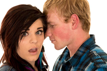 A man telling his woman a secret she has a shocked expression.の写真素材