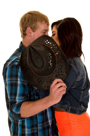 a man and woman sneaking a kiss behind a hat.の写真素材