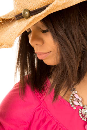 A woman in her cowboy hat and pink shirt looking down.の写真素材
