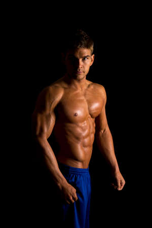 A man looking flexing his muscles, with a serious expression.の写真素材