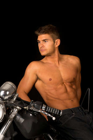 A man leaning back on his motorcycle with out a shirt on .の写真素材