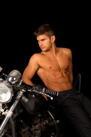 A man leaning back on his motorcycle with out a shirt on.の写真素材