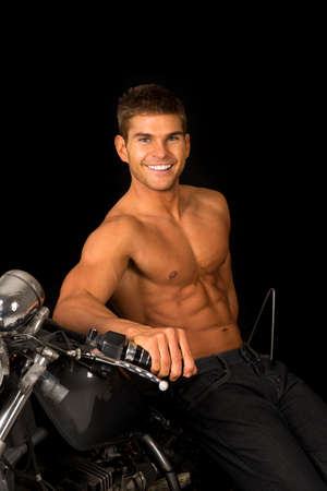 a man leaning back on his motorcycle with out a shirt, smiling.の写真素材
