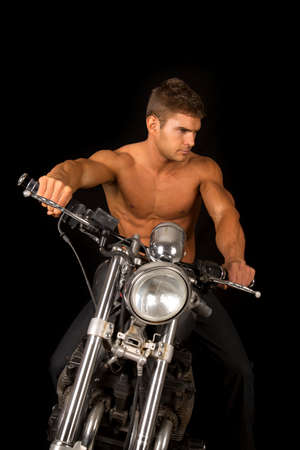 a man looking down to the side, while sitting on his motorcycle.の写真素材