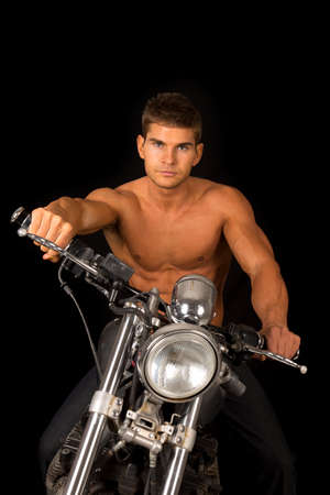 A man sitting on his motorcycle looking, he has no shirt on.の写真素材