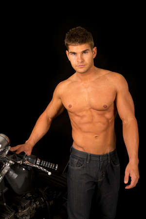 A man standing next to his motorcycle with no shirt on, with a serious expression.の写真素材