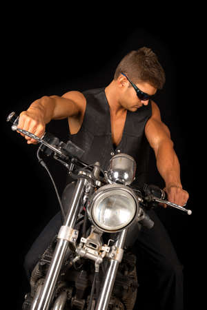 A man sitting on his motorcycle, with his black vest and sunglasses.の写真素材