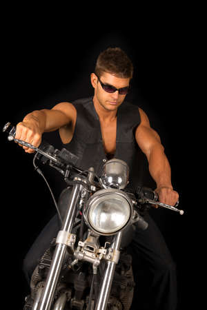 A man sitting on his motorcycle wearing his black vest and sunglasses.の写真素材