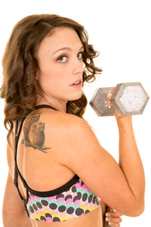a woman doing an arm curl with a owl tattoo on her shoulder.の写真素材