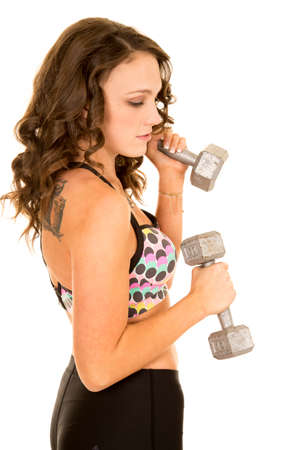 a woman holding on to her weights looking down working out her body.の写真素材