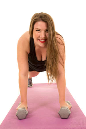 A woman with a big smile on her face, doing a push up on weights.の写真素材