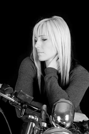 A black and white picture of a woman on a motorcycle  looking to the side.の写真素材