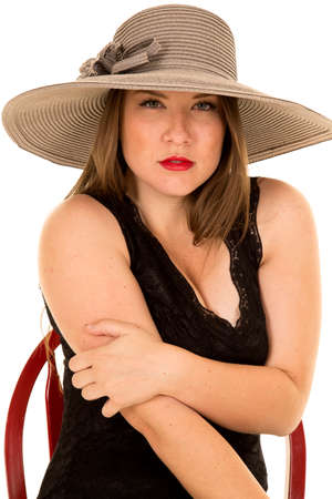 A woman sitting in a red chair wiith a gray hat on her head.の写真素材