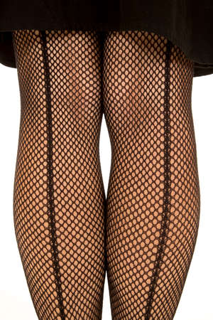 A close up of a woman legs in a black skirt wearing fishnet stockings.の写真素材