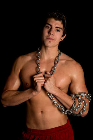 A man without a shirt on with a chain wrapped around his body.の写真素材