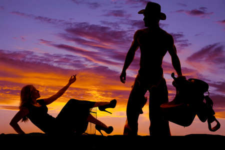 A silhouette of a woman in a dress reaching up towards her cowboyの写真素材