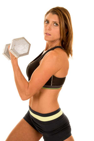 A woman with a serious expression on her face, doing an arm curl.の写真素材