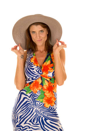 a woman touching the sides of her hat in her dress.の写真素材