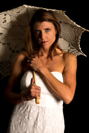 A woman with low light, under and umbrella.の写真素材