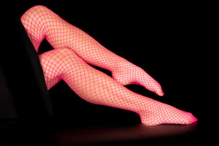 A close up of a womans legs in pink fishnet stockings.の写真素材