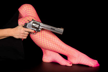A woman's legs in her pink fishnets with pistol by her leg.の写真素材